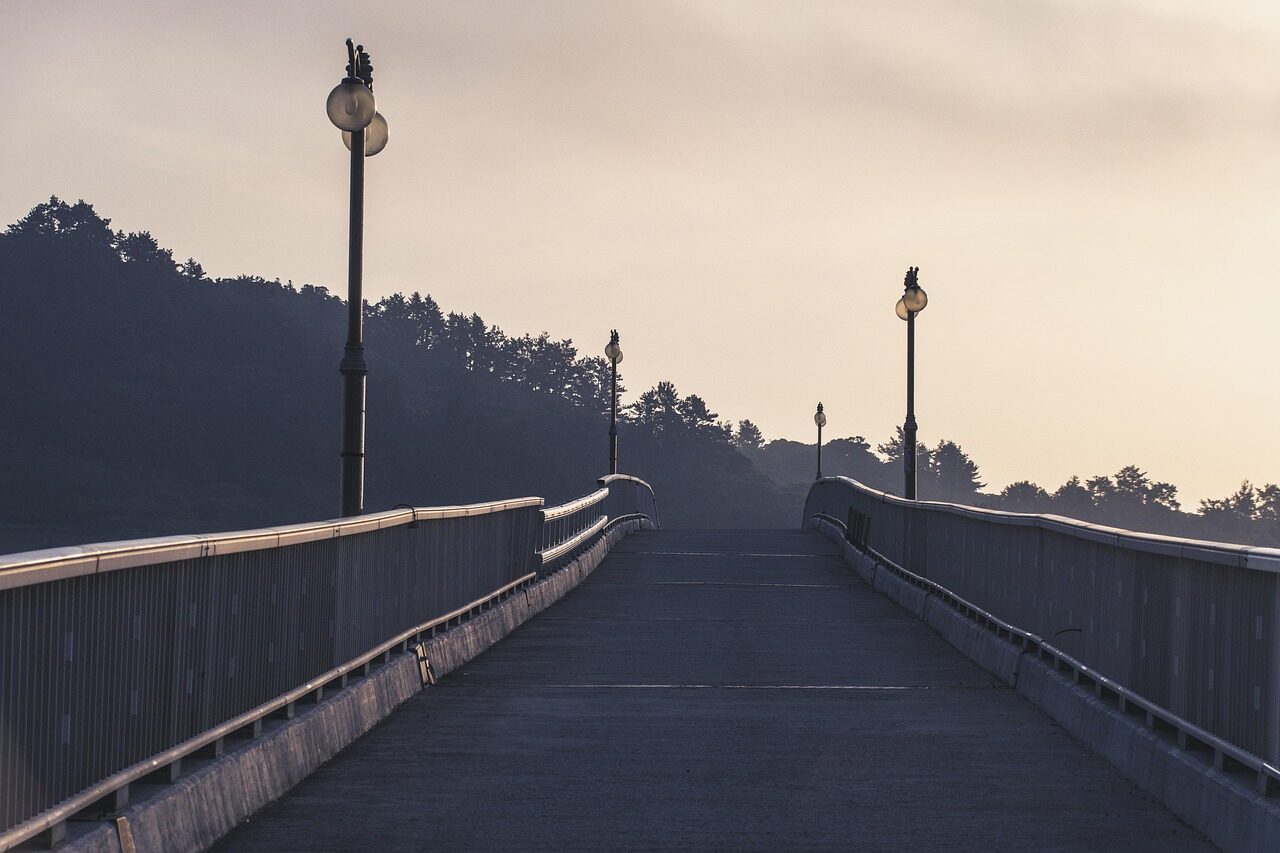 a wide wooden footbridge with lamp posts, leading to nowhere in particular but certainly somewhere specifically